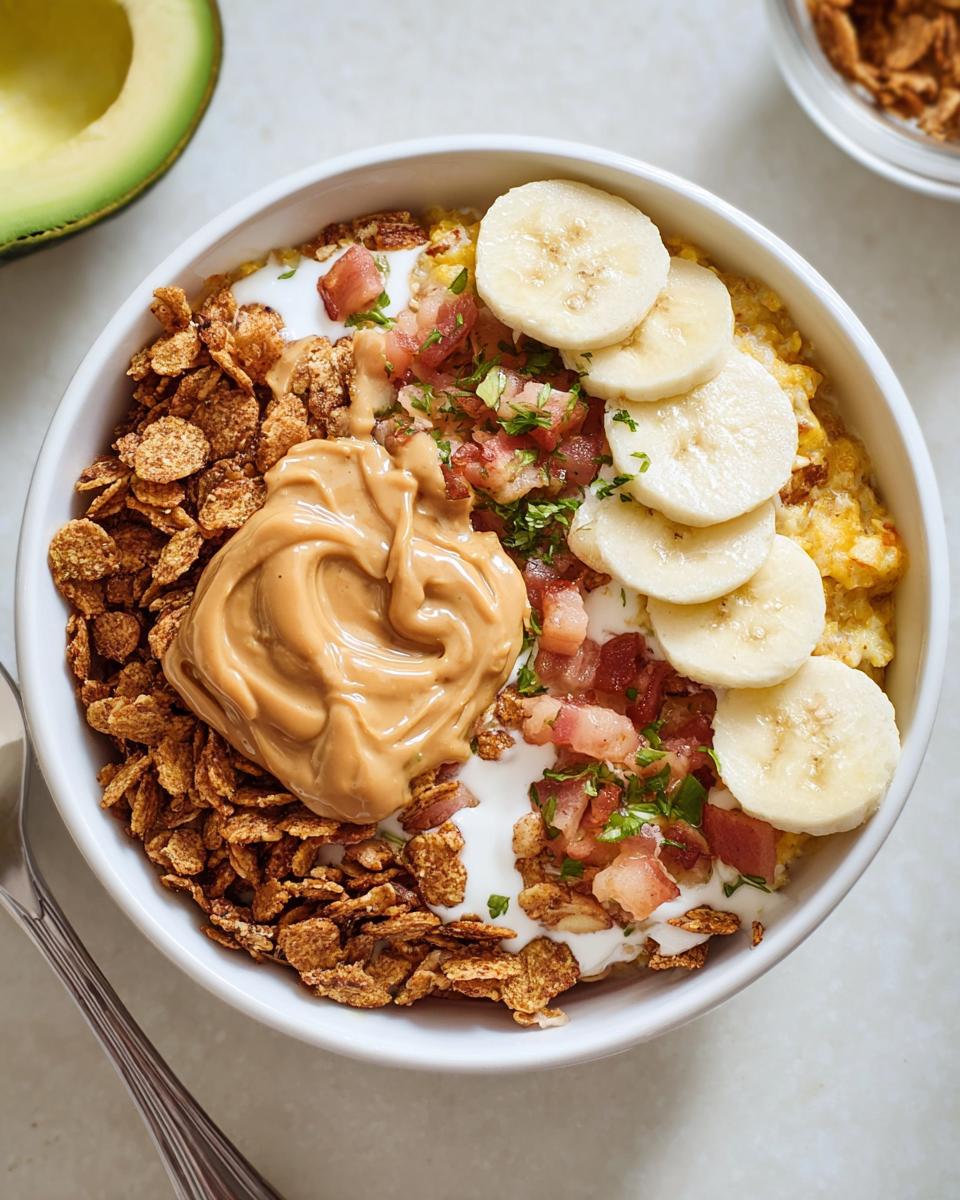 Overhead view of a High-Protein Breakfast Bowl topped with peanut butter, banana slices, cereal, and bacon bits.