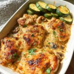 Three golden-brown chicken thighs baked in a creamy mushroom sauce, served with sliced zucchini for a Keto Chicken Family Dinner.