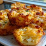 Close-up of golden brown Mashed Potato Bacon Cheese Puffs, baked in muffin tins and garnished with chives.