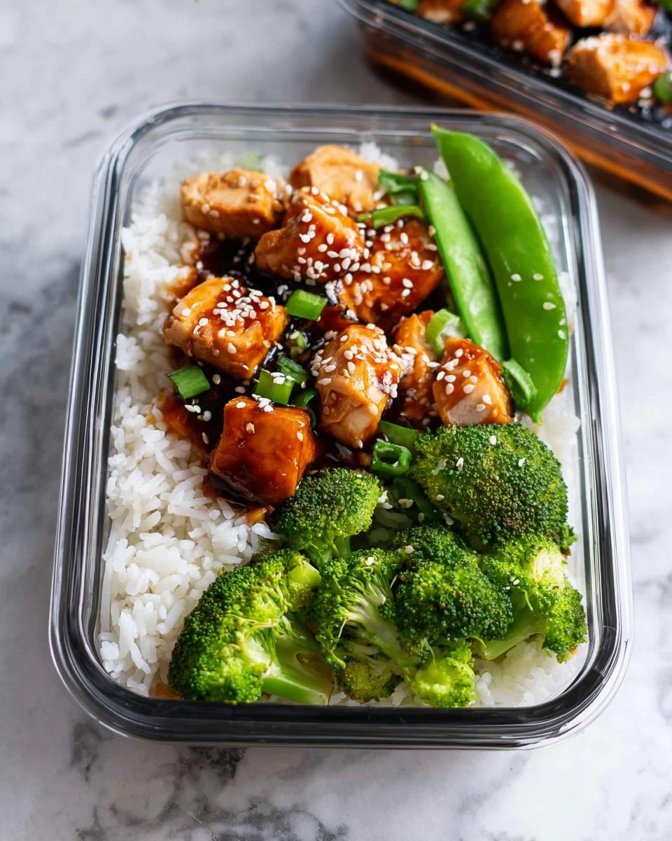 A glass container filled with Meal Prep Teriyaki Chicken Bowls featuring rice, glazed chicken, broccoli, and snap peas.