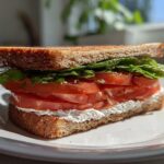 A vibrant Morning Toast Sandwich featuring toasted whole-grain bread, cream cheese, thick tomato slices, and lettuce.