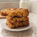 Stack of three baked oatmeal bars, perfect for Make-Ahead Breakfast for Busy Weeks, on a small white plate.
