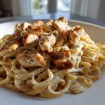 Close-up of creamy Parmesan Garlic Chicken & Noodles featuring fettuccine tossed in a rich sauce, topped with seasoned chicken pieces.