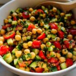 Close-up of a vibrant Quick Chickpea Salad featuring chickpeas, chopped tomatoes, and cucumbers in a white bowl.