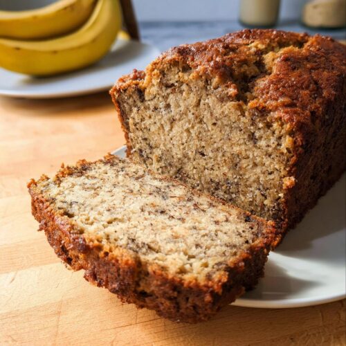 Close-up of a Rich Banana Sour Cream Loaf, showing a moist, speckled interior and a dark, caramelized crust.