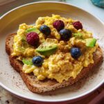 Scrambled eggs on toast topped with avocado, blueberries, and raspberries, perfect for a 5-Minute Breakfast.