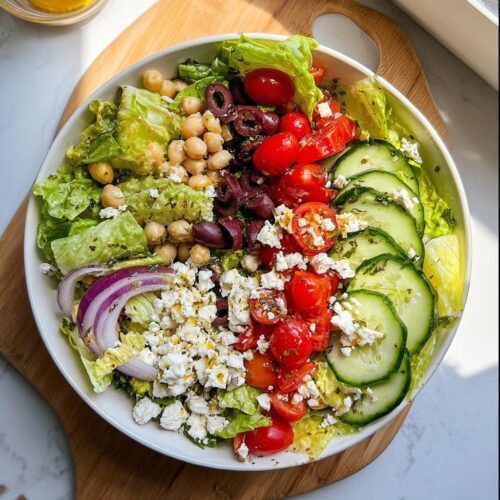 Overhead view of a Simple Mediterranean Lunch Salad featuring lettuce, chickpeas, tomatoes, cucumbers, olives, and feta cheese.