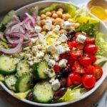 A vibrant bowl featuring a Simple Mediterranean Lunch Salad with chickpeas, feta, cucumbers, tomatoes, and red onion.