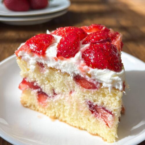 A generous slice of Strawberry Fruit Topped Cake featuring layers of sponge cake, cream, and fresh strawberries.