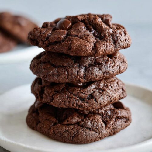 A tempting stack of four dark, fudgy Chocolate Espresso Cookies piled high on a white plate.