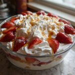 A large glass bowl filled with the Strawberry Banana Dream dessert, topped generously with whipped cream and fresh strawberries.