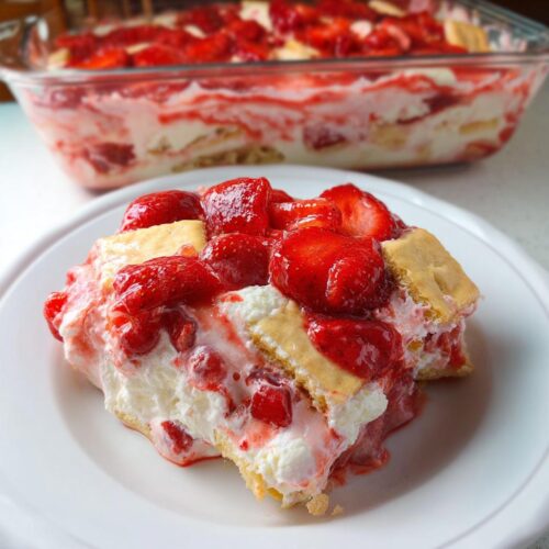 A generous slice of creamy Strawberry Banana Pudding topped with glazed strawberries on a white plate.