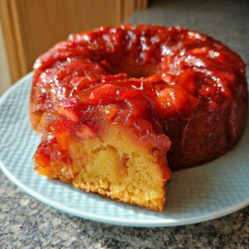 A slice cut from a glistening Strawberry Bundt Upside Down Cake, showing the moist crumb and caramelized strawberry topping.