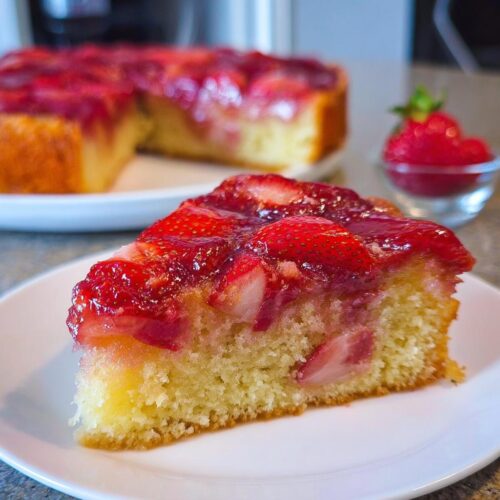 A close-up slice of moist Strawberry Sheet Upside Down Cake with caramelized strawberries on top.