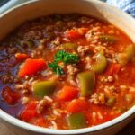 Close-up of a steaming bowl of Stuffed Pepper Dinner Soup with ground beef, rice, and chunks of green and red peppers.