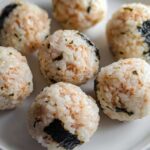 Close-up of several finished Tuna Sushi Ball Recipe portions arranged on a white plate.