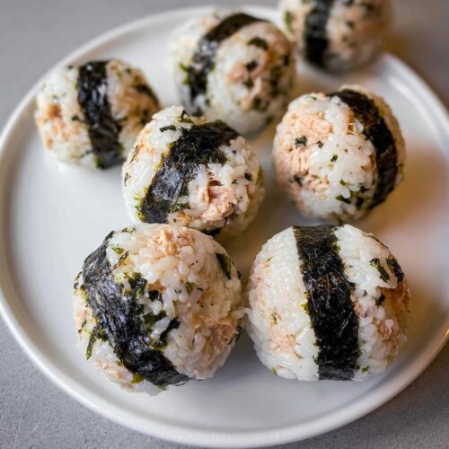 Close-up of six homemade Tuna Sushi Ball Recipe portions arranged on a white plate.