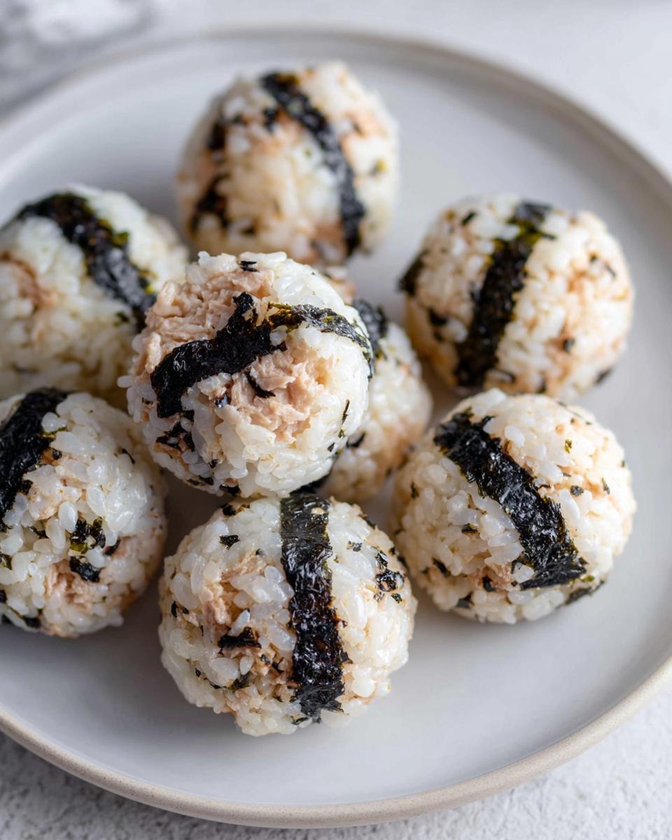 Close-up of several homemade Tuna Sushi Ball Recipe portions served on a light gray plate.
