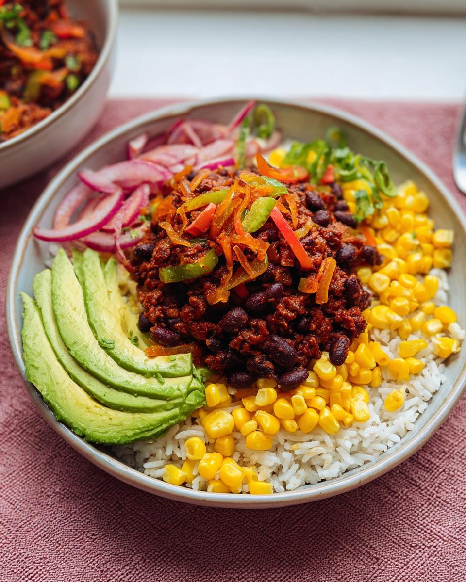 A vibrant Vegetarian Taco Rice Bowl featuring black beans, corn, avocado slices, and pickled onions over white rice.