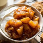 Close-up of a bowl containing creamy yogurt topped with warm apple chunks cooked in cinnamon sugar for a Warm Apple Breakfast.