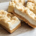 Three rich slices of White Chocolate Coconut Bars showing a thick, creamy white filling and crumbly topping on a graham cracker crust.