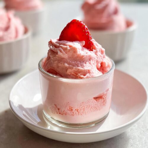 Close-up of fluffy pink 4-Ingredient Strawberry Mousse served in a small glass, topped with a fresh strawberry slice.