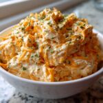 A white bowl filled high with creamy Cheddar Ranch Pretzel Dip, topped with shredded cheddar and fresh chives.