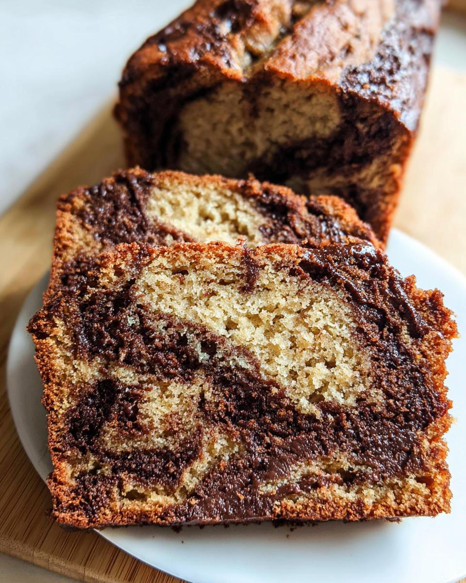 Close-up of two thick slices of Chocolate Swirl Banana Loaf showing the beautiful marble pattern of banana bread and chocolate batter.
