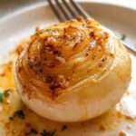 Close-up of a whole, tender onion prepared using the Classic Butter Onion Boil method, glistening with butter sauce.