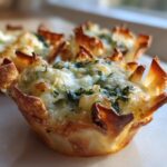 Close-up of a baked Classic Spinach Artichoke Wonton Cup with melted cheese topping.