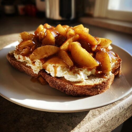 A slice of toasted bread topped with creamy cheese and caramelized, spiced apple slices, a perfect Comfort Breakfast Made with Apples.