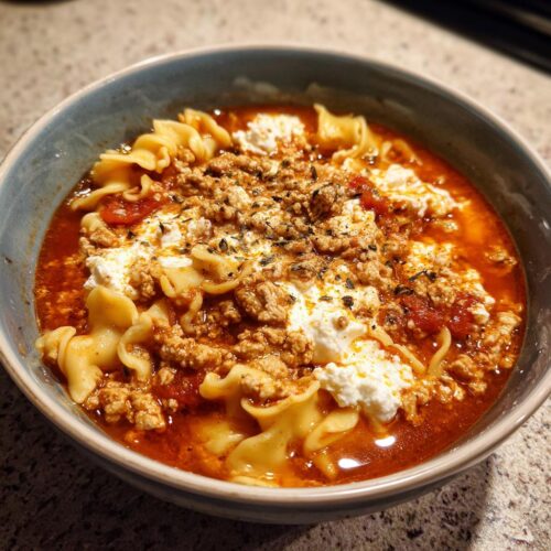 Close-up of a bowl of Cottage Cheese Lasagna Soup featuring pasta, rich tomato broth, ground meat, and dollops of cottage cheese.