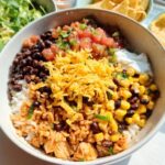 A vibrant bowl featuring rice, black beans, corn, salsa, sour cream, and shredded cheese for an Easy Mexican Rice Bowl.
