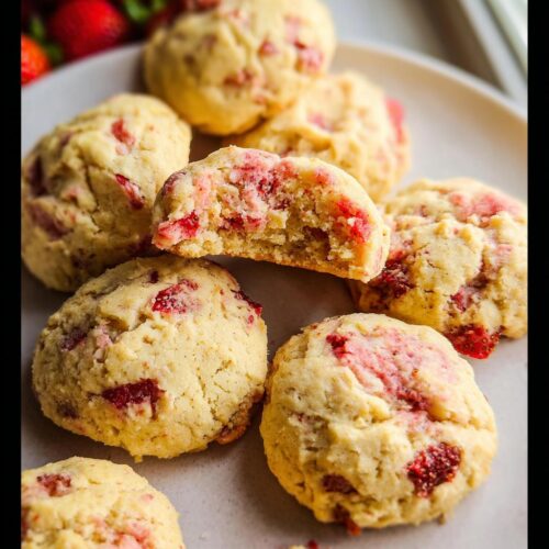 Close-up of soft, pale yellow Easy Strawberry Cookies, one broken open showing the pink strawberry filling.