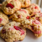 A stack of soft, freshly baked Easy Strawberry Cookies, with one cookie broken in half showing the moist interior.