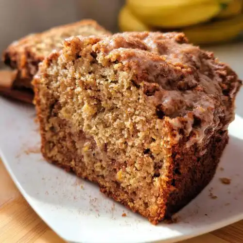 Close-up of a moist slice of Fall Cinnamon Banana Bread topped with a light glaze and cinnamon.