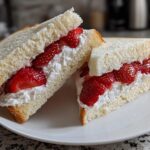 Two halves of a Fresh Strawberry Sando featuring thick white bread, whipped cream, and sliced bright red strawberries.