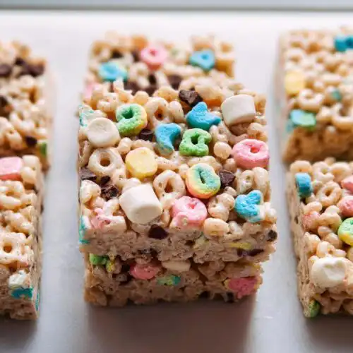 Close-up of stacked Lucky Charms Rice Krispie Treats featuring colorful marshmallows and chocolate chips.