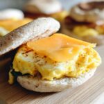 Close-up of a Breakfast Sandwich You Can Meal Prep featuring scrambled egg, melted cheddar cheese, and spinach on an English muffin.
