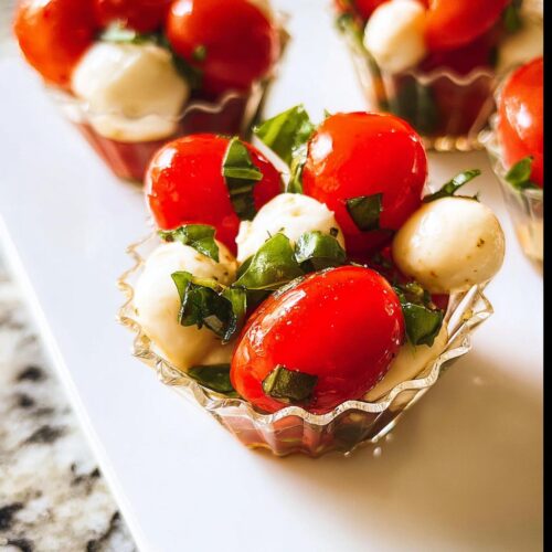 Close-up of one of the Mini Caprese Cups filled with cherry tomatoes, small mozzarella balls, and fresh basil.