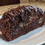 Close-up of a slice of Moist Chocolate Banana Cake topped with a rich chocolate glaze drizzle.