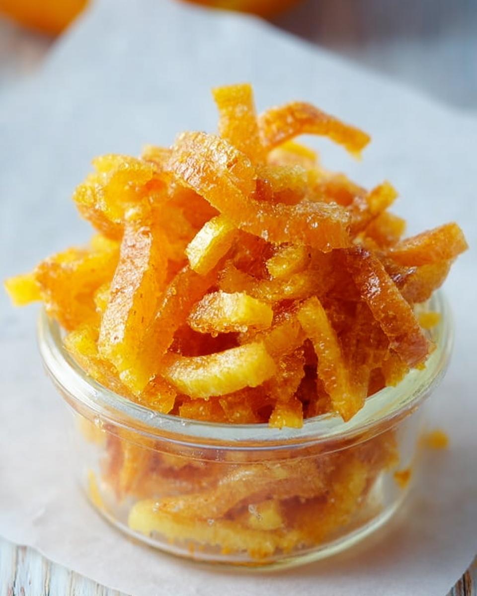 Close-up of glistening, candied Orange and Lime Mixed Peel strips piled high in a small glass jar.