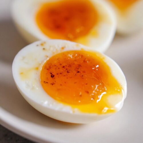 Close-up of a halved Soft Boiled Eggs with Jammy Centers, seasoned lightly, showing a bright orange, slightly runny yolk.