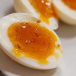 Close-up of a halved Soft Boiled Eggs with Jammy Centers, seasoned with pepper, showing a perfectly cooked white and gooey yolk.