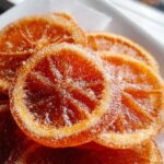 Close-up of glistening, deep orange Candied Orange Slices with Brown Sugar coated in sparkling sugar crystals.