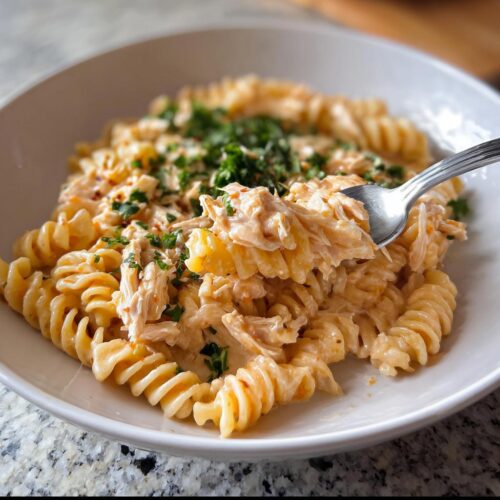 A close-up of creamy Protein-Packed Chicken Pasta with fusilli noodles and shredded chicken, garnished with parsley.