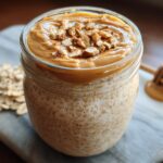 Close-up of Blended Peanut Butter Overnight Oats in a jar, topped with creamy peanut butter and chopped nuts.