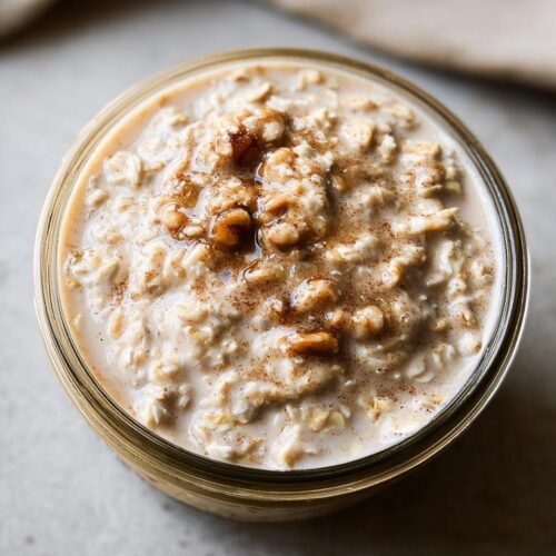 Overhead view of creamy Brown Sugar Maple Overnight Oats topped with nuts and cinnamon in a glass jar.