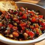 A bowl filled with fresh, diced tomatoes, herbs, and a rich balsamic glaze, served with a piece of toasted bread for the Bruschetta Dip.