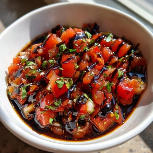 A white bowl filled with fresh Bruschetta Dip with Balsamic Glaze, featuring diced tomatoes and herbs.